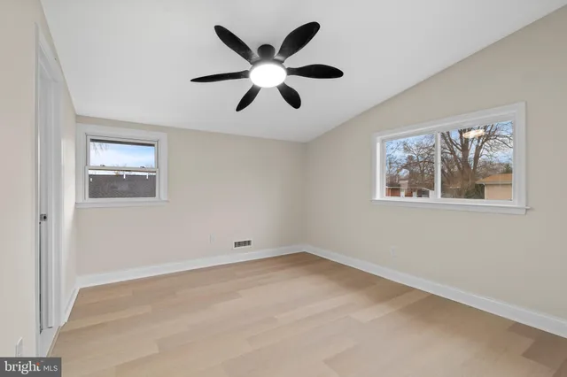 a view of an empty room with window and ceiling fan