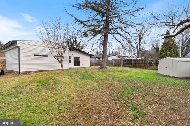 a backyard of a house with large trees and brick wall