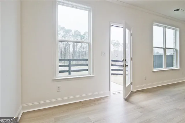 an empty room with wooden floor and windows