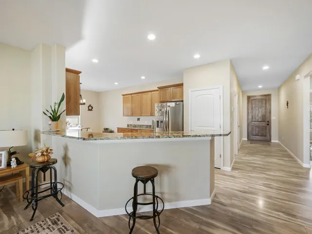 a living room with stainless steel appliances kitchen island a table chairs in it and wooden floor