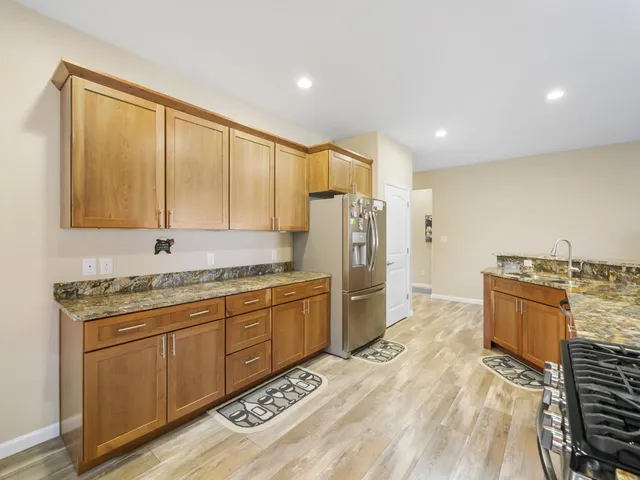 a large kitchen with stainless steel appliances granite countertop a stove a sink and a refrigerator