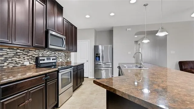 a kitchen with stainless steel appliances granite countertop a sink refrigerator and microwave