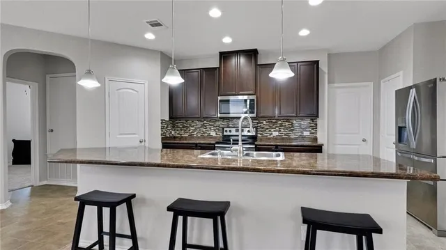 a large kitchen with a table chairs refrigerator and microwave