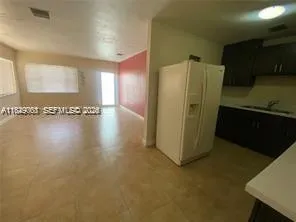 a view of a refrigerator in kitchen and an empty room