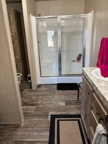 a bathroom with a granite countertop sink a mirror and a shower