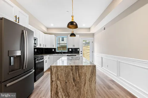 a large kitchen with stainless steel appliances granite countertop a stove a sink dishwasher and a refrigerator with wooden floor