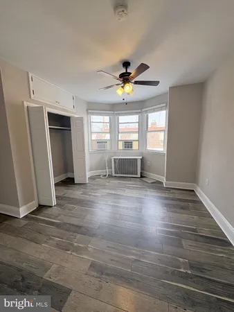 a view of an empty room with window and wooden floor
