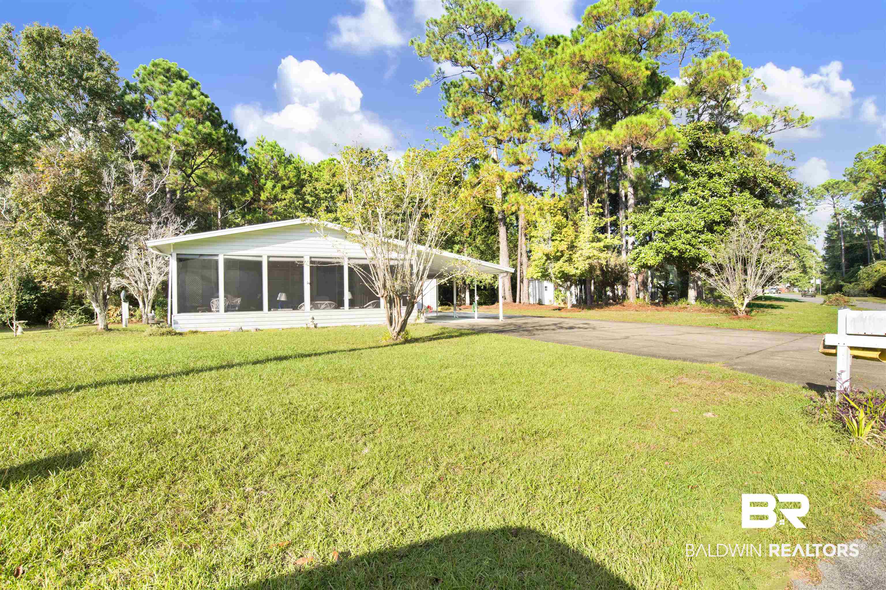 1216 Ridgewood Drive Lillian, AL 36549 - Photo 29 of 29 View of green lawn with an attached carport, concrete driveway, and a sunroom