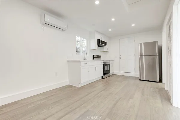 a view of a kitchen with a sink refrigerator and wooden floor