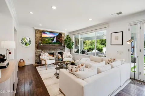 a living room with fireplace furniture and a large window