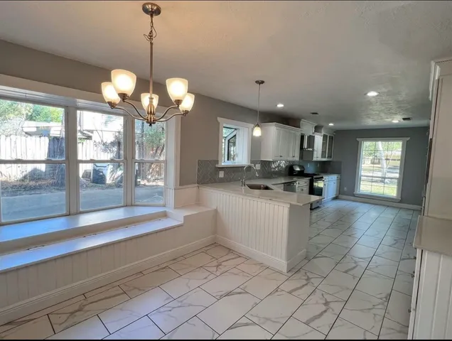 a large kitchen with white cabinets and chandelier