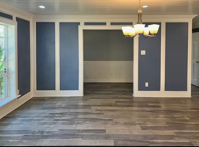 a view of a hallway with chandelier and wooden floor