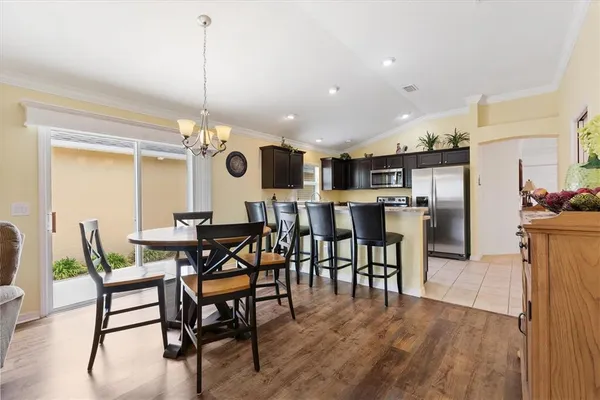 a view of a dining room and livingroom with furniture wooden floor a rug a painting and a chandelier