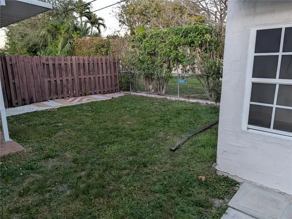 a view of a backyard with wooden fence and a large tree