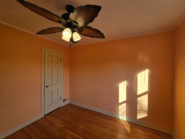 a view of an empty room with wooden floor and windows