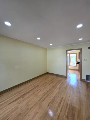 a view of an empty room with wooden floor and closet