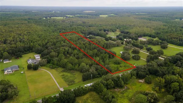 an aerial view of a residential houses with outdoor space and trees