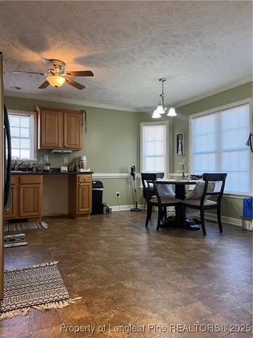 a open kitchen with stainless steel appliances granite countertop a stove dining table chairs and a refrigerator