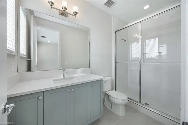 a bathroom with a granite countertop sink toilet a mirror and shower
