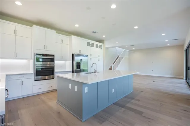 a kitchen with stainless steel appliances kitchen island wooden floors and white cabinets