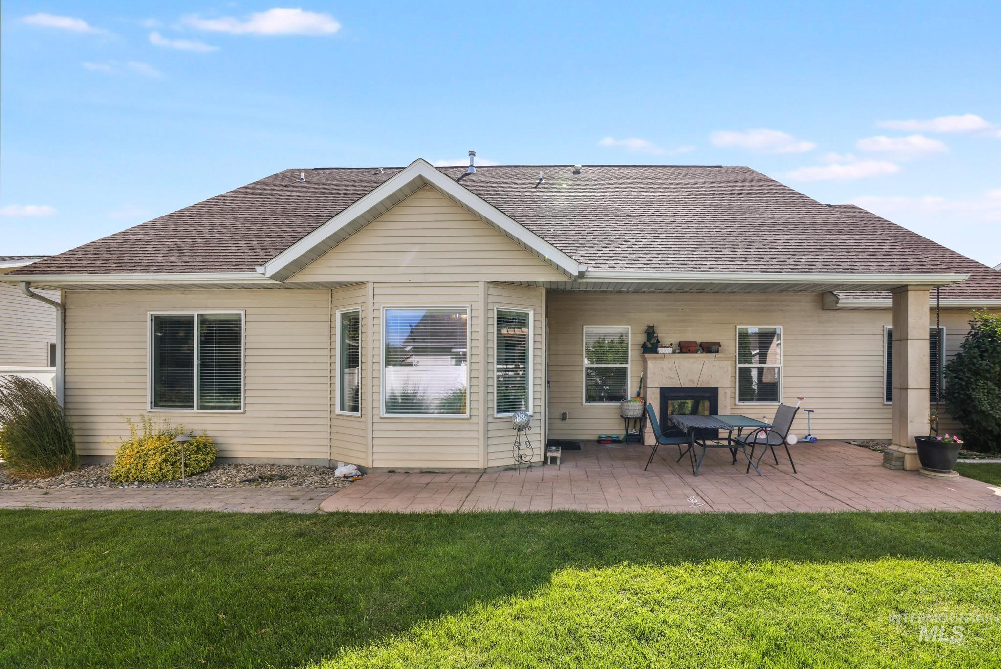 467 Wildrose Loop Twin Falls, ID 83301 - Photo 40 of 46 Rear exterior featuring a spacious paved patio, built-in outdoor fireplace, covered porch area, bay window, and a manicured lawn