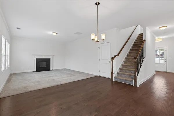 a view of a livingroom with wooden floor staircase and a kitchen