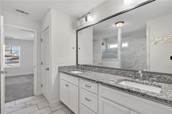 a spacious bathroom with a granite countertop sink a mirror and shower