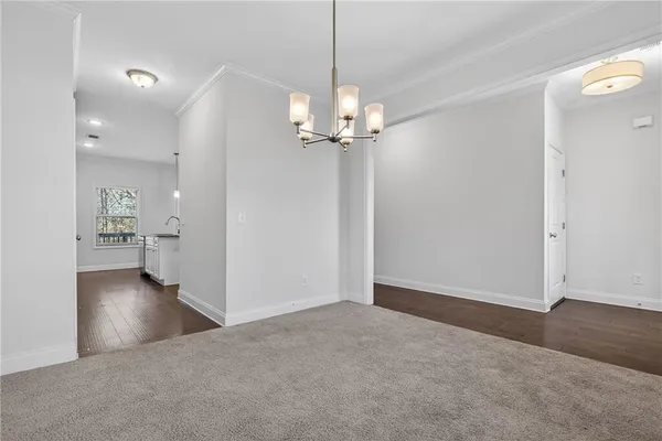 an empty room with kitchen view and a chandelier