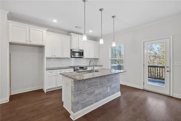 a kitchen with kitchen island granite countertop a stove a sink a center island a refrigerator and a wooden floor