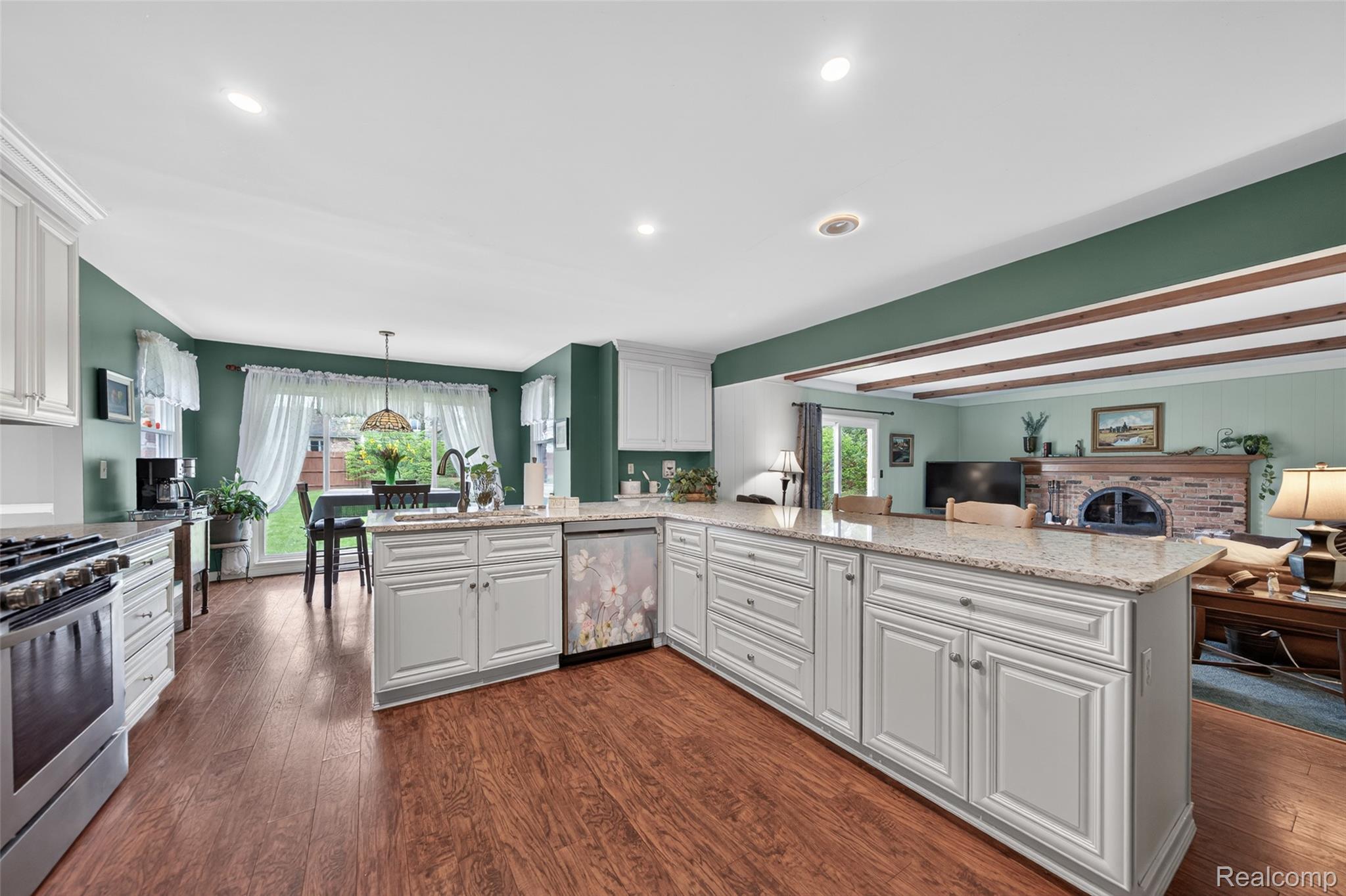 2578 Powderhorn Ridge Road Rochester, MI 48309 - Photo 15 of 46 Kitchen featuring light stone counters, stainless steel appliances, dark wood-style flooring, and a brick fireplace