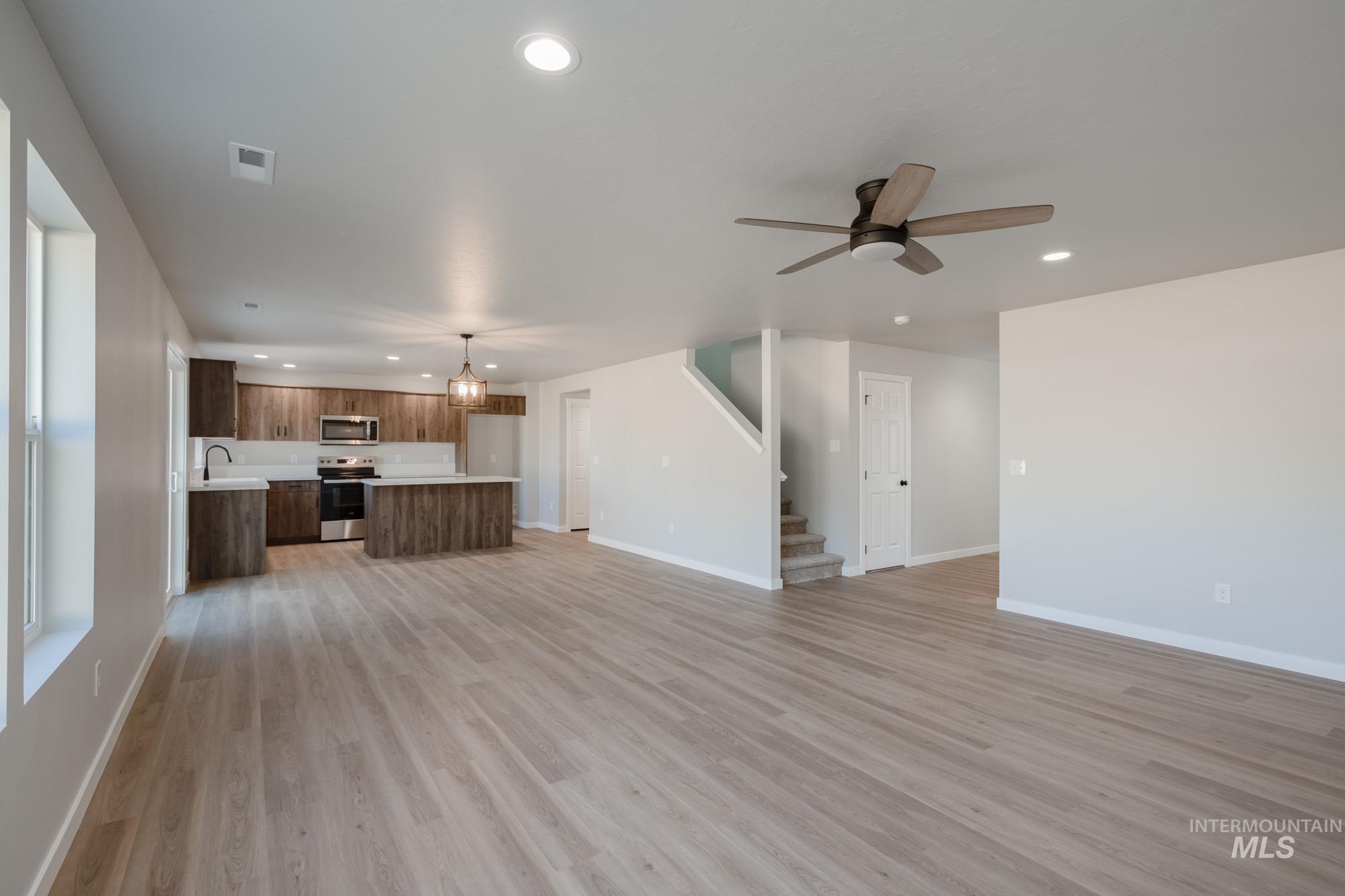 13727 Judson Street Caldwell, ID 83607 - Photo 13 of 26 Unfurnished living room featuring recessed lighting, light wood-type flooring, a ceiling fan, stairs, and a chandelier