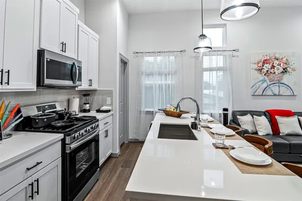 a kitchen with stainless steel appliances a stove a sink dishwasher a microwave oven with cabinets and wooden floor