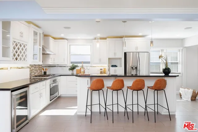 a kitchen with stainless steel appliances granite countertop a table chairs sink and cabinets