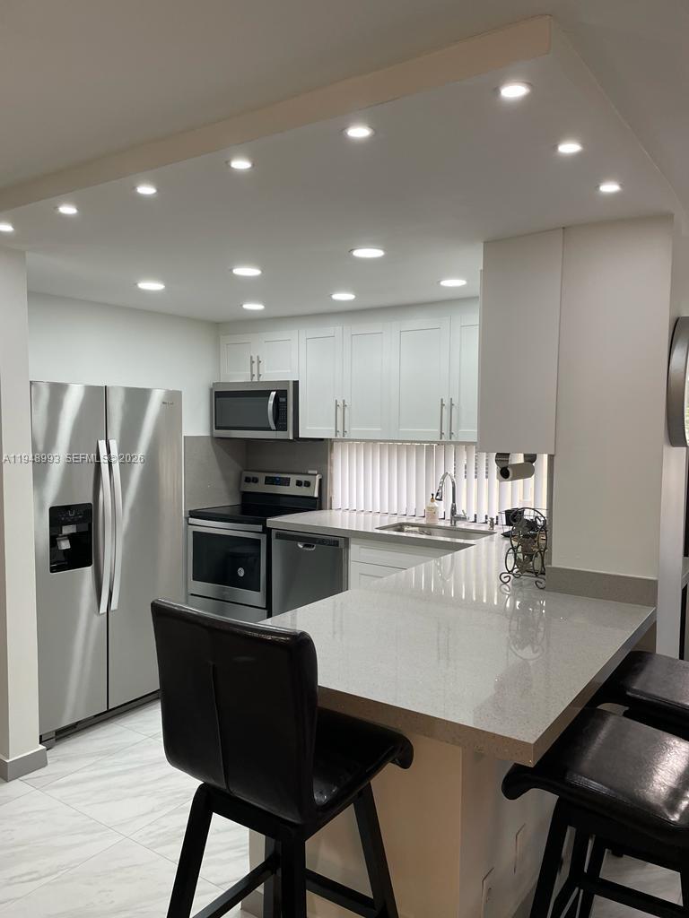 16919 North Bay Road, Unit 104 Sunny Isles Beach, FL 33160 - Photo 5 of 32 a kitchen with a dining table cabinets and refrigerator