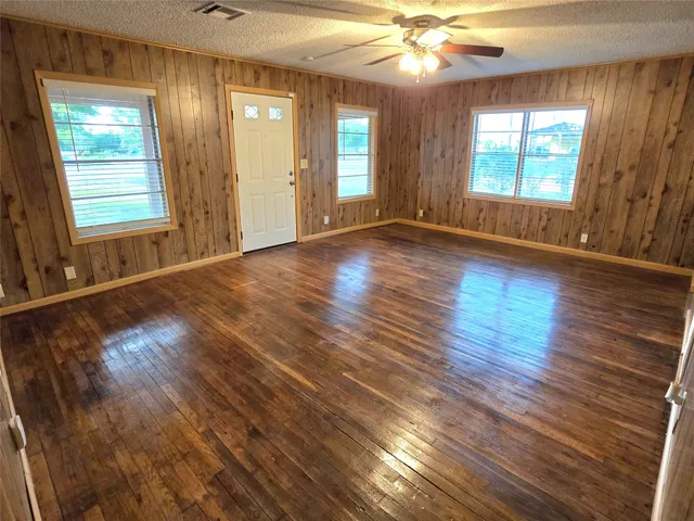 an empty room with wooden floor and windows