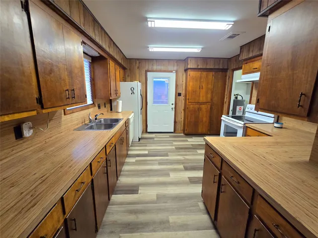 a view of a kitchen with refrigerator and wooden floor