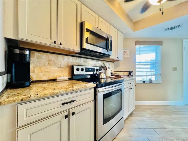 a kitchen with granite countertop white cabinets stainless steel appliances and a counter space