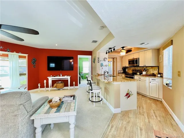a living room with stainless steel appliances kitchen island granite countertop a couch and a flat screen tv