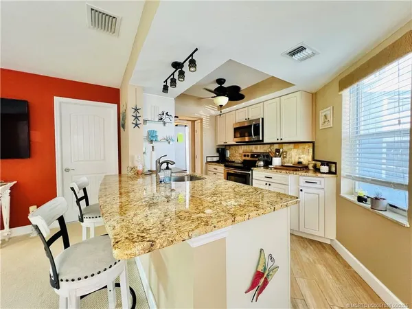 a kitchen with kitchen island granite countertop a sink cabinets and stainless steel appliances