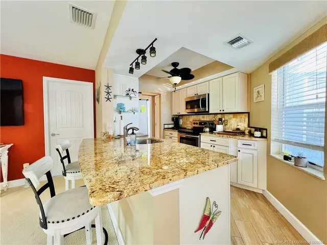 a kitchen with kitchen island granite countertop a sink cabinets and stainless steel appliances