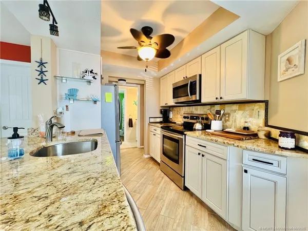 a kitchen with granite countertop a sink stainless steel appliances and white cabinets