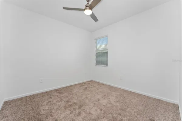 an empty room with a ceiling fan and a window