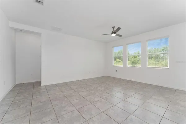 an empty room with windows and ceiling fan