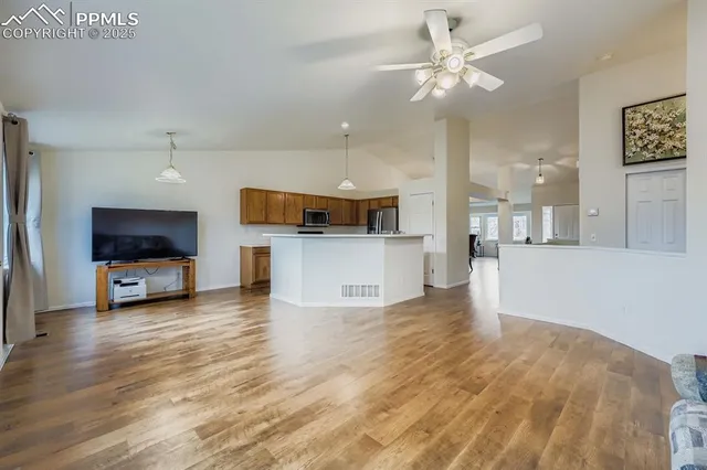 a living room with stainless steel appliances kitchen island furniture and a flat screen tv