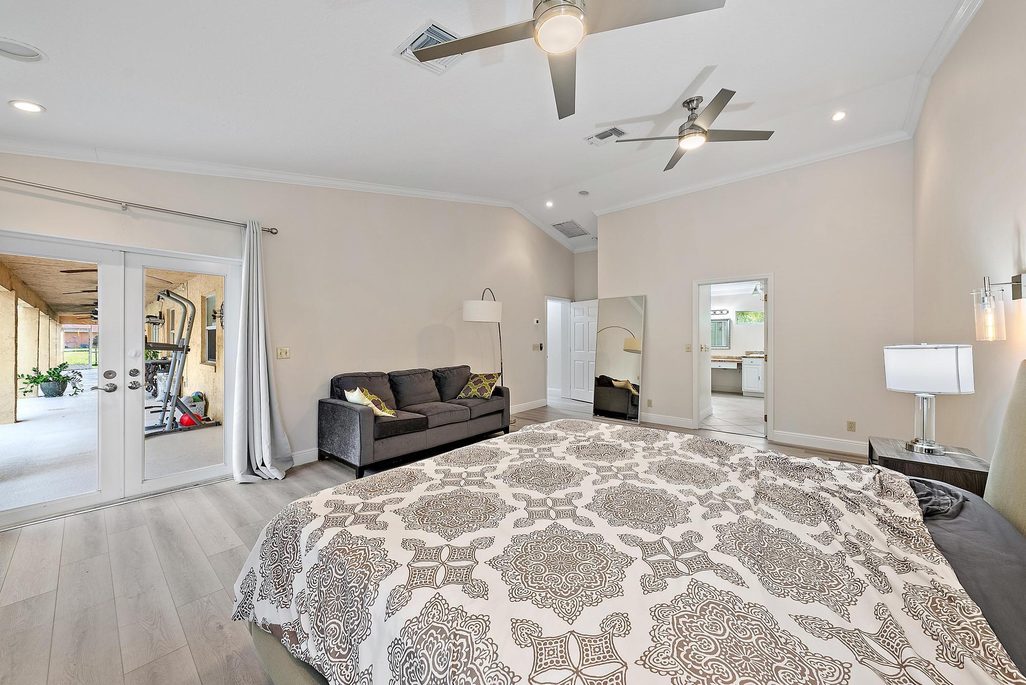 16338 Alexander Run Jupiter, FL 33478 - Photo 12 of 32 a bedroom with a large bed and ceiling fan