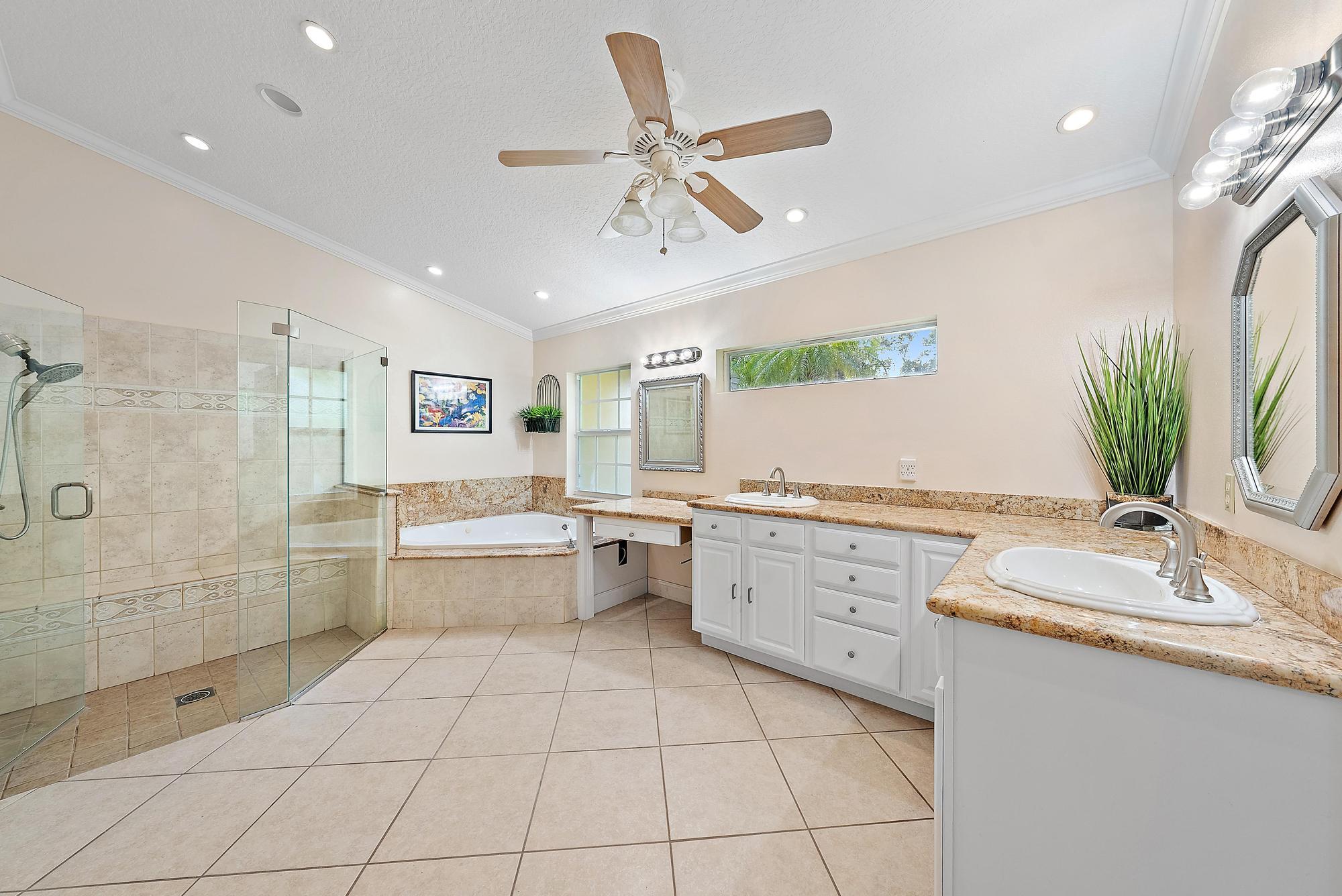 16338 Alexander Run Jupiter, FL 33478 - Photo 13 of 32 a large white bathroom with a granite countertop sink mirror and bathtub