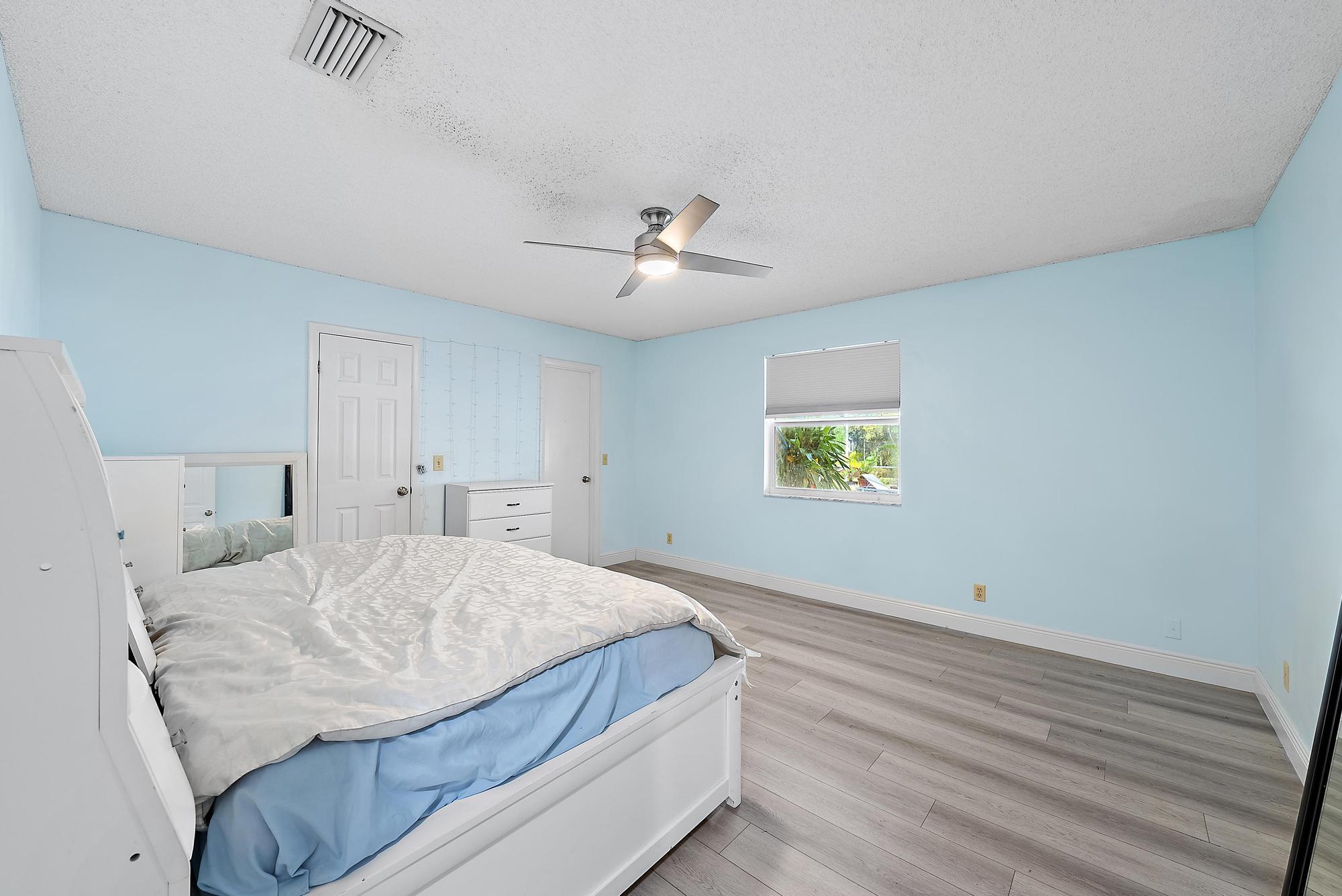 16338 Alexander Run Jupiter, FL 33478 - Photo 16 of 32 a bedroom with a bed and a chandelier