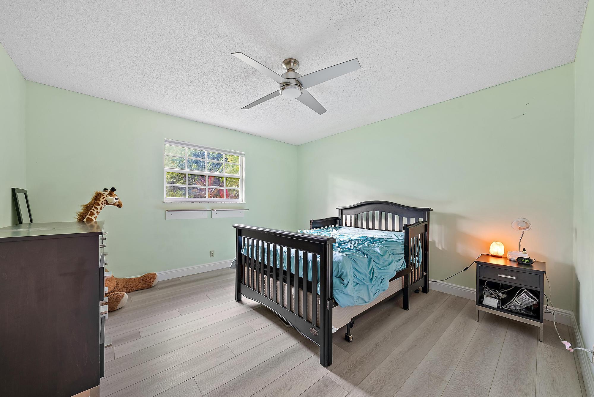 16338 Alexander Run Jupiter, FL 33478 - Photo 17 of 32 a bedroom with a bed and a wooden floor