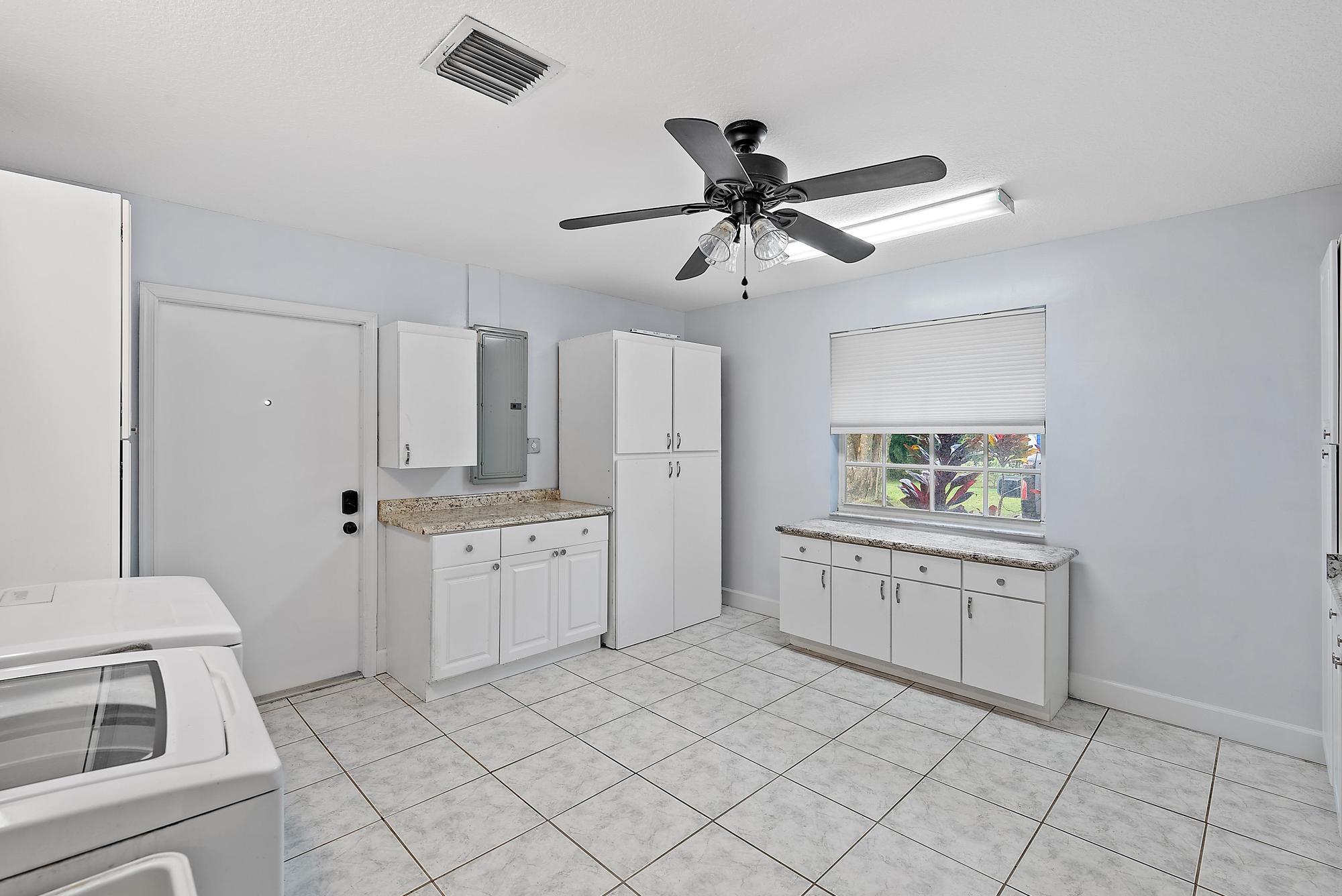 16338 Alexander Run Jupiter, FL 33478 - Photo 19 of 32 a kitchen with white cabinets and appliances