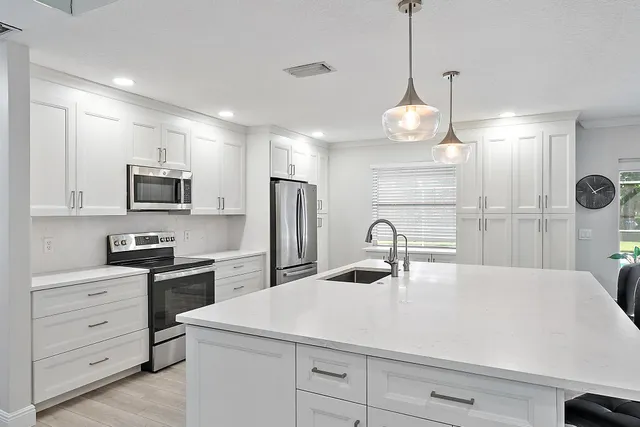 a kitchen with kitchen island a sink stainless steel appliances and cabinets